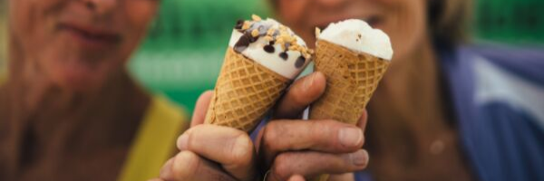 two ice cream cones held in hands close to each other