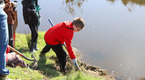 Young kid preparing soil for planting along Stemple Creek - MALT