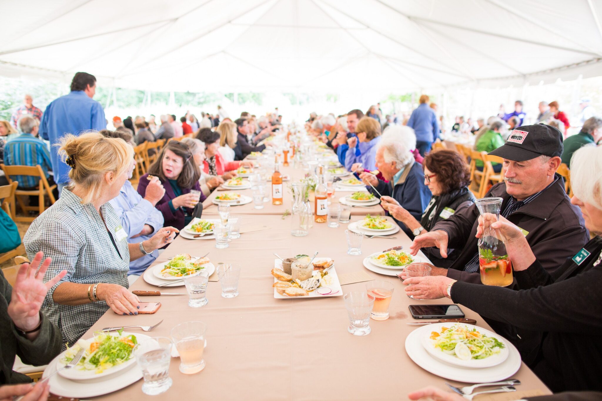 People sit at a long farm table, eating greens and bread at a brunch. Photo from Lynn Bagley Photography from a Ranches and Rolling Hills MALT event.