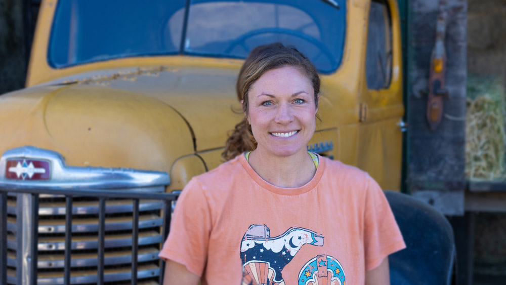 Marissa Silva stands smiling in front of a yellow vintage truck at Marshall Home Ranch