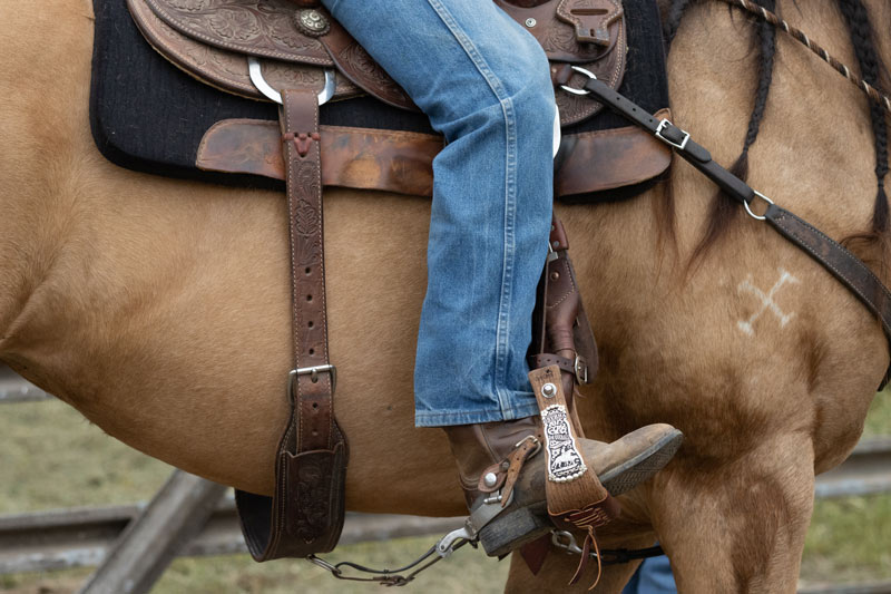 Cowboy's leg in jeans in saddle.